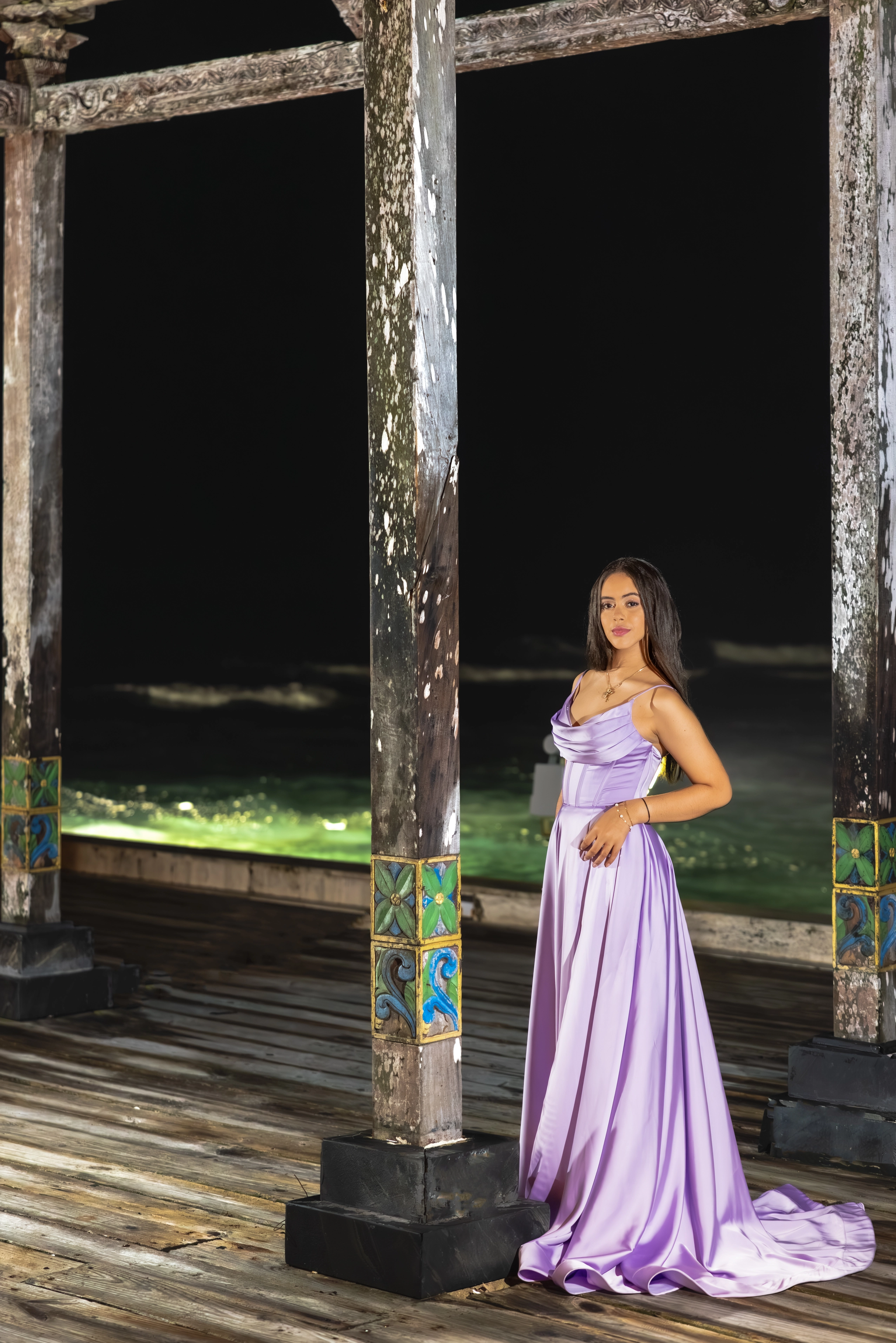 Quinceañera in a flowing dress posing on the beach